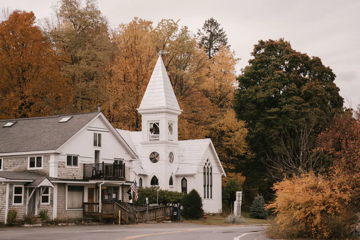 A white New England church and homes among autumn trees in a small Maine town